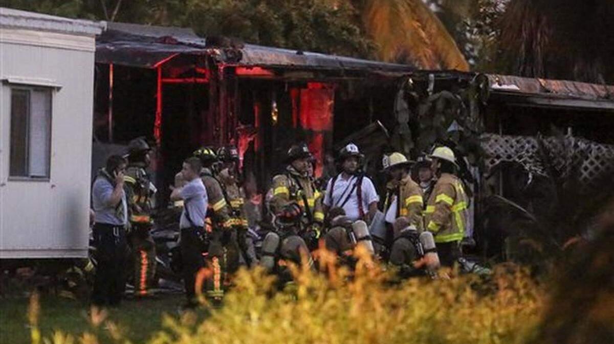 Bomberos se reúnen después de apagar un incendio causado cuando un avión pequeño se estrelló en un aparcamiento de casas móviles en Lake Worth, Florida, el martes 13 de octubre de 2015. La aeronave golpeó varias casas en el Club Colonial Mar-Mak. (Bruce R. Bennett/Palm Beach Post via AP) MAGS OUT; TV OUT; NO SALES; MANDATORY CREDIT