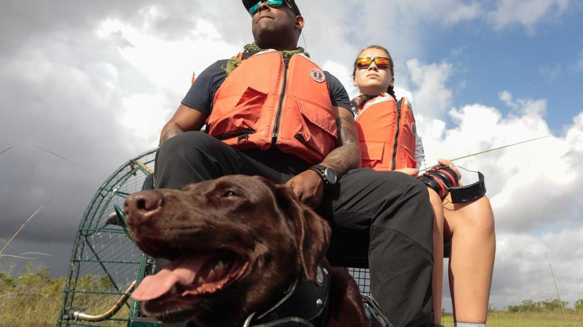 Chad Brown, a la izquierda, monta en un hidrodeslizador junto a Riley Brooks y su perro Axe.