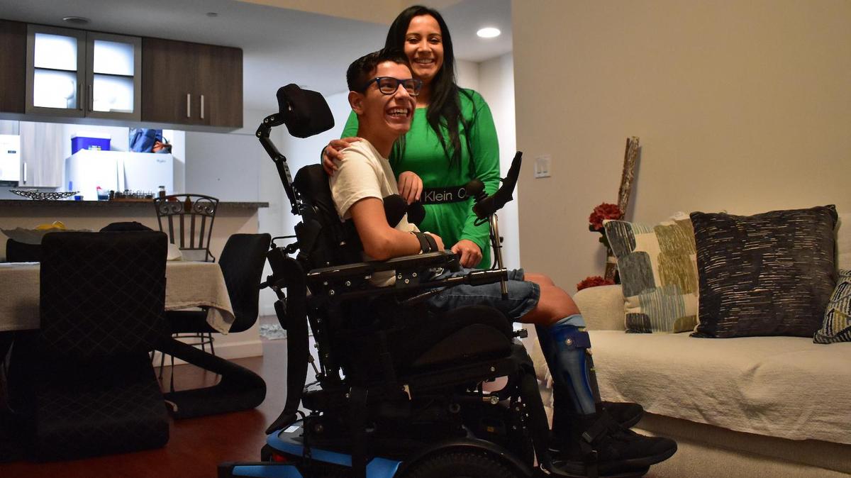 Diana Bustamante y su hijo, Juan Luna, en la sala de su departamento. Juan tiene parálisis cerebral y su madre necesita equipos para ayudarle a levantarse de su silla de ruedas y de su cama.