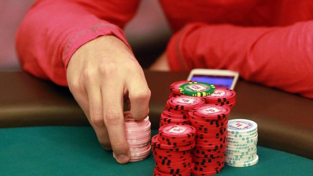 Un hombre sostiene sus fichas mientras juega una partida de poker en el Hialeah Park & Casino.