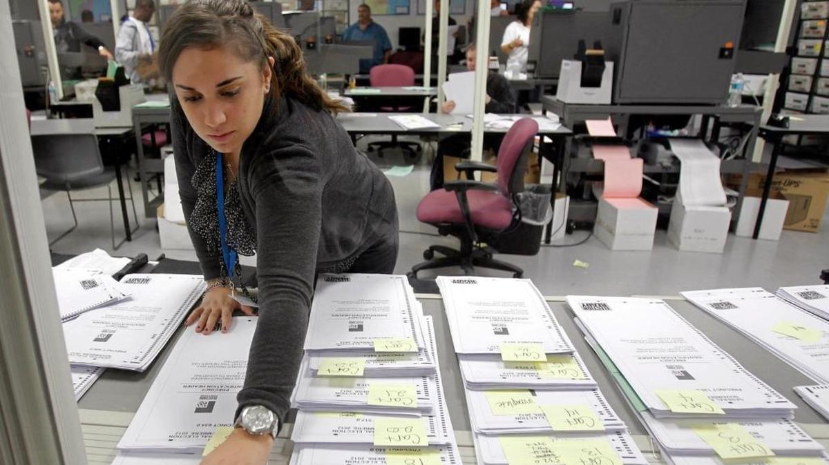 Una funcionaria del Departamento de Elecciones del condado Miami-Dade inspecciona un grupo de votos ausentes en Doral, en el 2012.