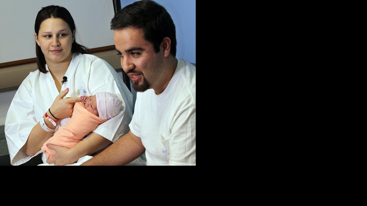 
La joven mamá Arielle Larken sostiene en brazos a su recién nacida hija Addison, mientras su esposo Daniel Dávila habla con la prensa el jueves en el Hospital Jackson Memorial.
