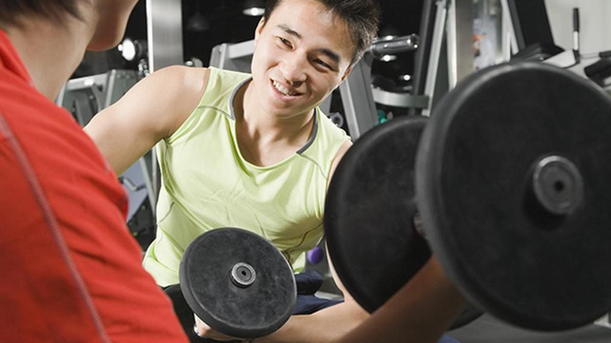 Dos jóvenes realizan ejercicios con pesas en un gimnasio.