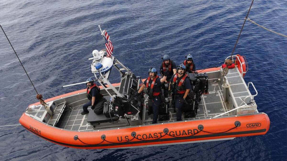 Un equipo de guardacostas desciende de un navío en un bote pequeño. Foto de archivo.