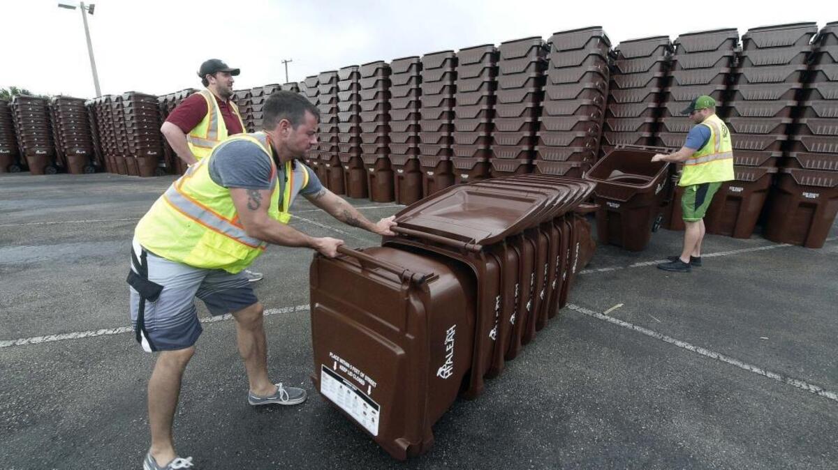 De izquierda a derecha, Kevin Woodley, Jud Hasper y Sonny Pelhan, organizan los contenedores para basura de la Ciudad de Hialeah.