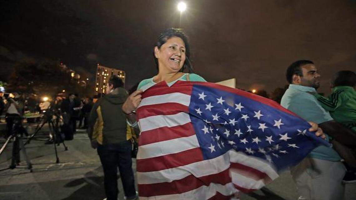 Viviana Ivalo, de Argentina despliega la bandera estadounidense en Miami después del discurso del Presidente sobre inmigración.