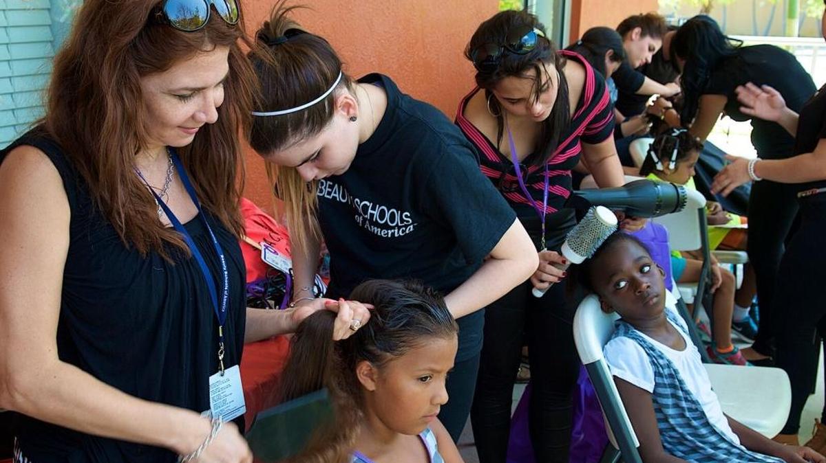 
La maestra de cosmetología de BSA, Maribel Oviedo, supervisa a sus alumnas mientras cortan el pelo a estudiantes de diferentes escuelas de la comunidad que asistieron a uno de los eventos en Little Haiti Soccer Park. 
