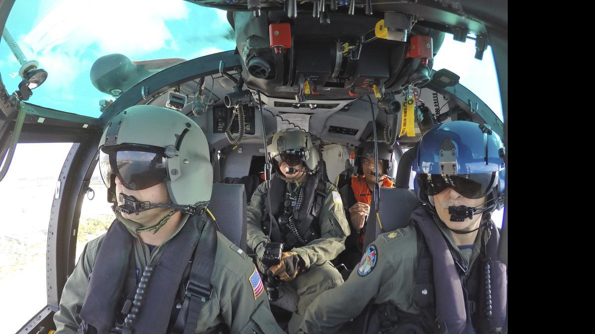 
El comandante Whitney Keith (der.), el copiloto John Fleischli (izq.), y el mecánico de vuelo Eric Gould (centro) vuelan abordo de un helicóptero MH-65 Dolphin de la Guardia Costera de EEUU, sobre la costa de Miami Beach, el 19 de mayo de 2015.
