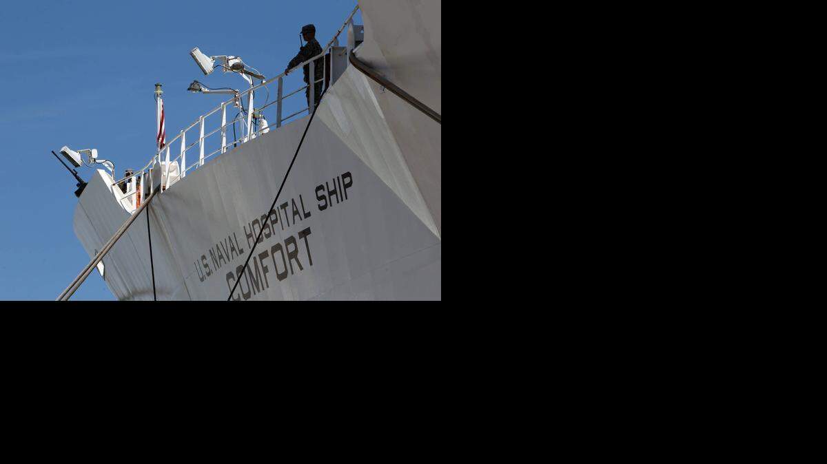 Dos militares estadounidenses montan guardia en el buque hospital USNS Comfort en el puerto de Miami el sábado. El USNS Comfort saldra de viaje con voluntarios de Operación Sonrisa por cinco meses.<252><252>