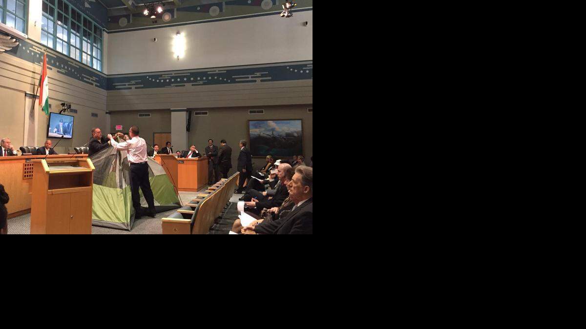 
Dos personas arman una carpa el jueves durante la reunión de la Comisión de Miami. Los comisionados debatieron una propuesta para prohibir el uso de tiendas de campaña en la ciudad. 
