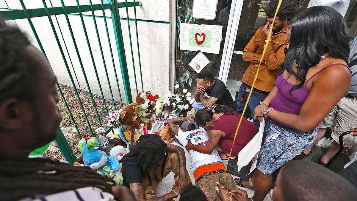 Santonio Carter sobre el improvisado altar que se ha hecho en el lugar donde jugaba su hijo King Carter, de 6 años.