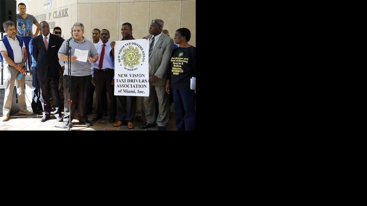 
Choferes de la compañía Uber realizan una protesta en downtown Miami el viernes, para exigir que su servicio sea legalizado en el condado Miami-Dade. John Busto, centro, miembro de New Vision Taxi Drivers Association, lee un comunicado durante el evento. 
