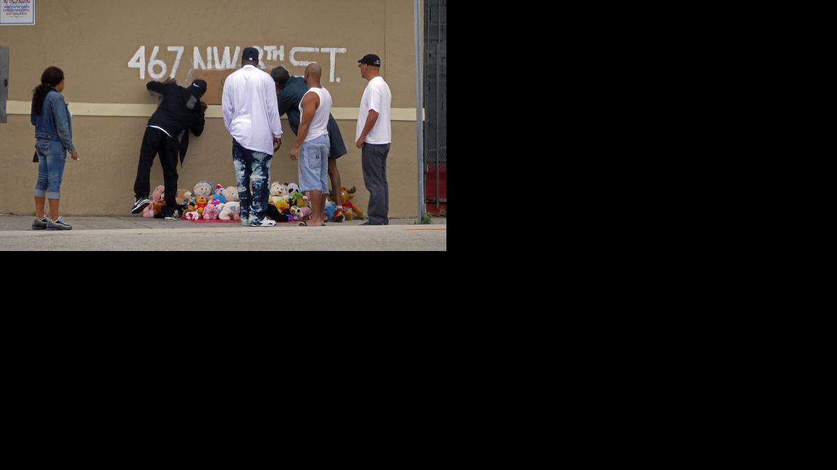 Los dolientes firman una especie de memorial el viernes en las afueras de la tienda donde donde tres personas fueron abaleadas. 