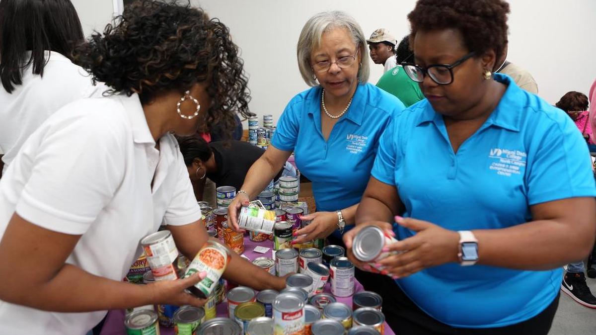 H. Leigh Toney (primera de la derecha), directora ejecutiva del Centro de Educación Empresarial Carrie P. Meek y miembro de AKA, ordena los donativos junto con Dawn Houston y Michael Mason.