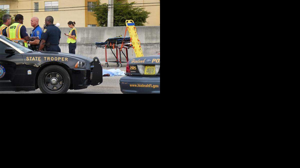 
ACCIDENT AFTERMATH: Police and Fire Rescue officials from the City of Hialeah gather near the body of Angela Johnson, 24 as she lies on the Palmetto Expressway near Okeechobee Road in Hialeah after being struck by a Ford Explorer. Johnson, along with two adults and seven children, tried to cross the busy highway on Thursday, January 1, 2015 on their way to a Chuck E. Cheese. An autopsy showed that Johnson was pregnant with her second child at the time of her death. Her daughter Kayla Johnson, 4, is in critical condition and two of Kayla’s cousins, ages 7 and 9, are in stable condition at Jackson Memorial. The two other adults were not injured. The State Attorney’s Office is weighing whether to charge the adults with endangering the children. 
