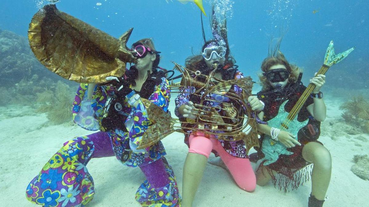 Varios participantes pretenden tocar las esculturas de instrumento musical de un artista local en el Underwater Music Festival en el Santuario Marino Nacional de Florida Keys de Big Pine Key, Florida