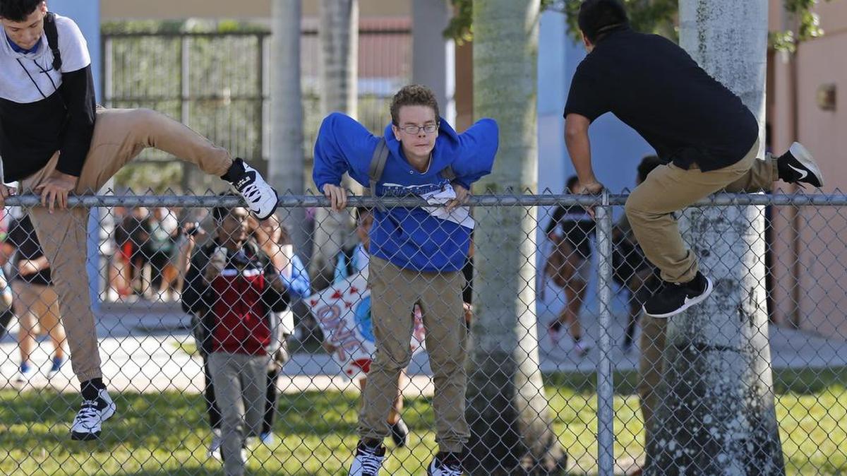 Estudiantes de la secundaria South Dade Senior High School saltan la cerca de la escuela para unirse a los manifestantes en Homestead.