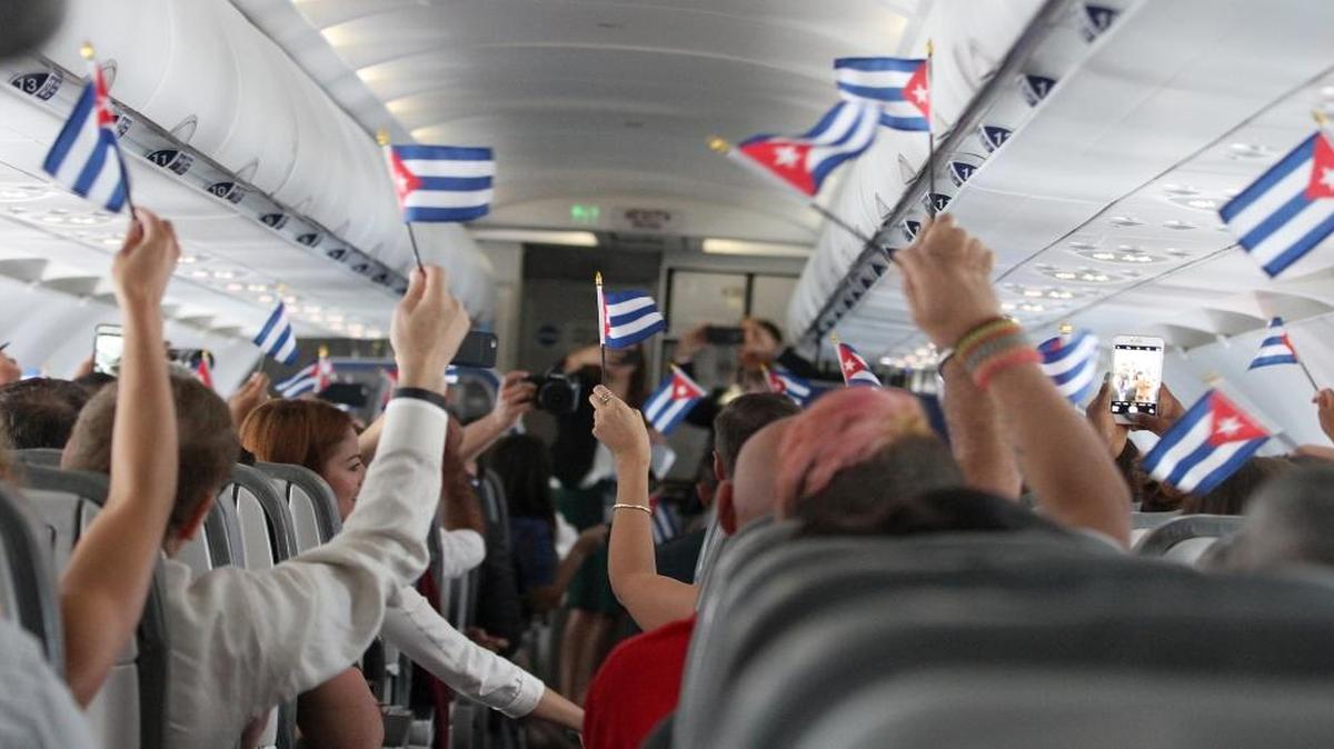 Los pasajeros del primer vuelo comercial de JetBlue a Cuba ondean pequeñas banderas cubanas poco después de despegar de Fort Lauderdale el 31 de agosto del 2016.