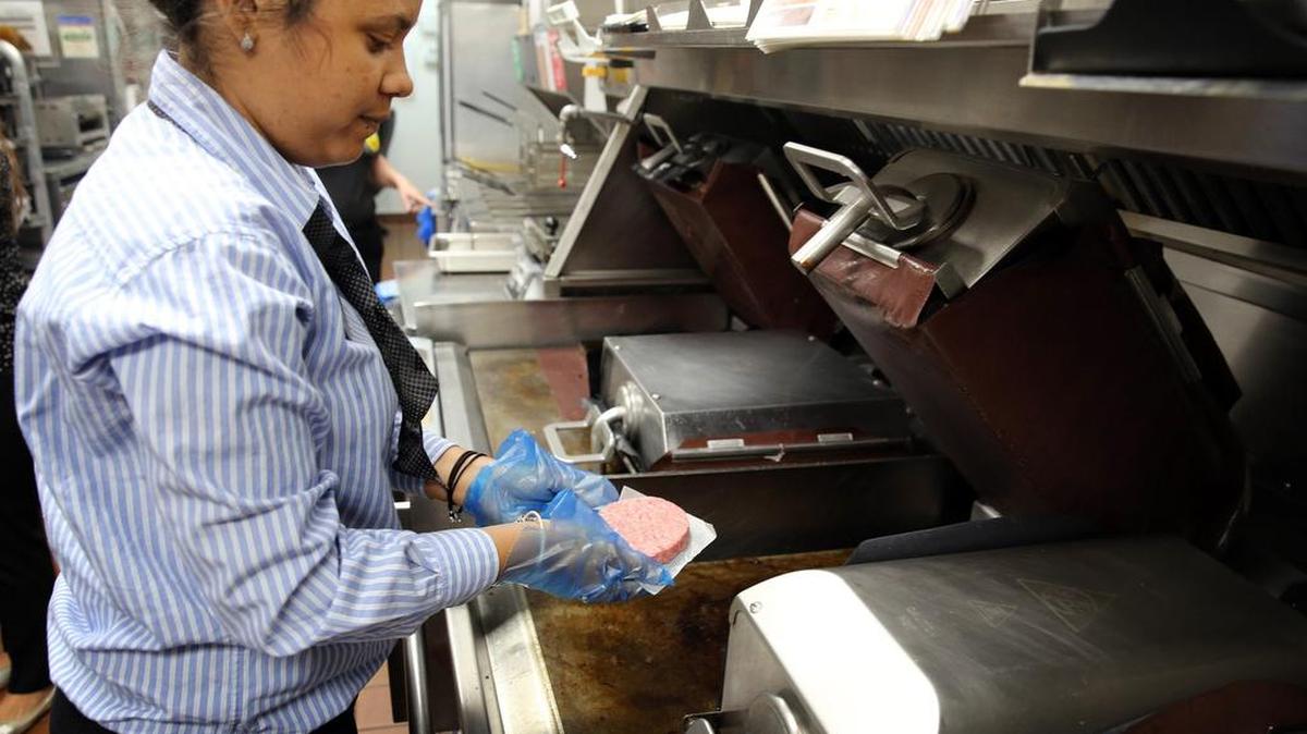 La gerente Katerina Córdova coloca el lunes una hamburguesa de carne fresca en el asador en el McDonald’s de la Calle Ocho y la Avenida 14 en La Pequeña Habana. Miami será una de ocho ciudades donde la cadena de los arcos de oro probará el uso de carne fresca en sus hamburguesas de un cuarto de libra y otros sandwiches.