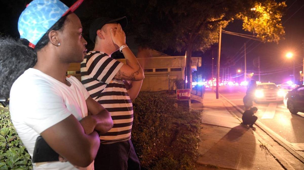Jermaine Towns, izquierda, y Brandon Shuford esperan en la calle tras un tiroteo múltiple en un club nocturno en Orlando, Florida.