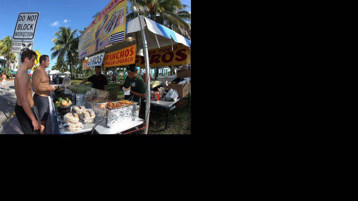 
Desde North Carolina, Carmer Vadini (izq.) y su padre Michael Vadini disfrutan del buen clima y del sabor local durante el Art Deco Weekend de Miami Beach.


