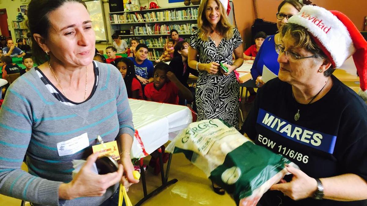 Terry Miyares entrega bolsas de alimentos a Magdalena Mora, cuyo hijo José, de 5 años, estudia en la primaria James H. Bright, en Hialeah. Foto: Enrique Flor