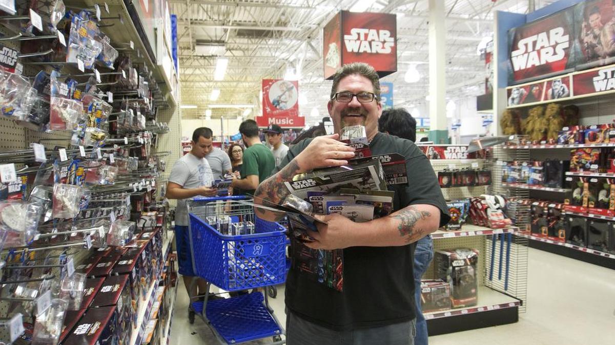 
Con una amplia sonrisa Tom Brownell carga los brazos llenos de mercancía de la Guerra de las Galaxias que encontró en Toys R Us.
