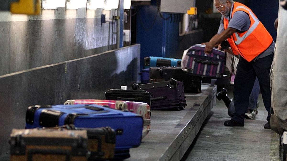 Un empleado de la zona de equipajes del Aeropuerto Internacional de Miami (MIA) descarga maletas que habían llegadoen un vuelo internacional. foto de archivo.