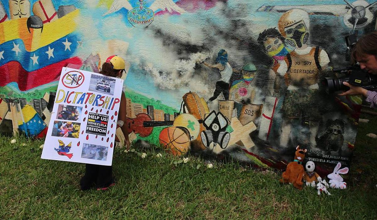 Maria Emilia Bavaresco coloca flores en el mural homenaje a los caídos en las protestas antigubernamentales en Venezuela.