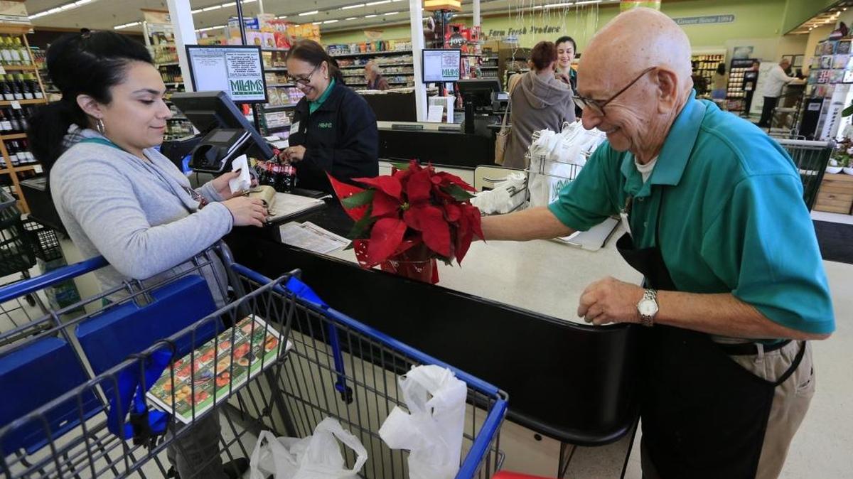 Antonio Guasp pone en bolsas la mercancía de una clienta en el Milan Supermarket de Miami Springs, el 15 de diciembre.