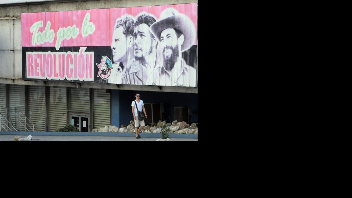 
Un hombre camina frente a una valla alusiva al nuevo aniversario de la Revolución cubana, en La Habana (Cuba). Foto de archivo.