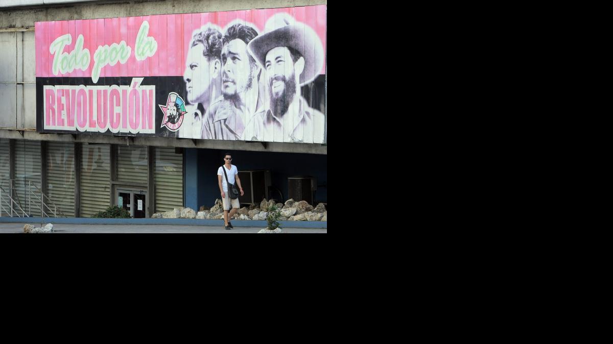 
Un hombre camina frente a una valla alusiva al nuevo aniversario de la Revolución cubana, en La Habana (Cuba). Foto de archivo.