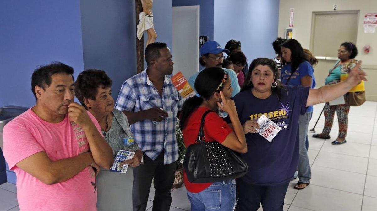 Joaquín Salgado (izq.) espera, junto a otras personas, para ser hablar con un consejero durante el foro organizado por la Coalición de Inmigrantes de Florida.