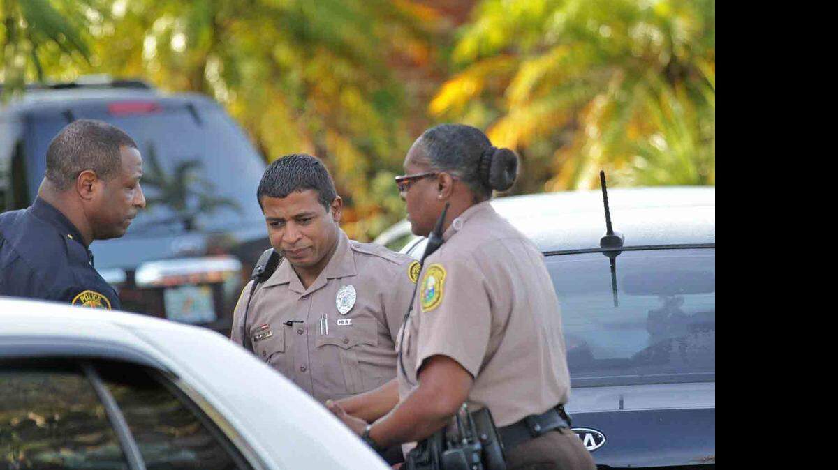 Tres oficiales de policía guardan silencio por un momento, luego de encontrar el cuerpo del ex director de la Policía de Miami-Dade Robert Parker.