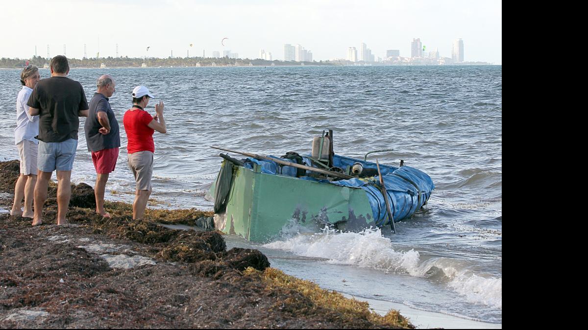 Bañistas toman fotos de una balsa hecha de metal, madera y espuma de poliestireno que llegó a la costa con un grupo de trece cubanos el 27 de mayo de 2015. La Ley de Ajuste Cubano fue aprobada en noviembre de 1966 y otorga al Fiscal General la discreción de conceder la residencia permanente en Estados Unidos a ciudadanos cubanos una vez que se encuentran en territorio estadounidense.
