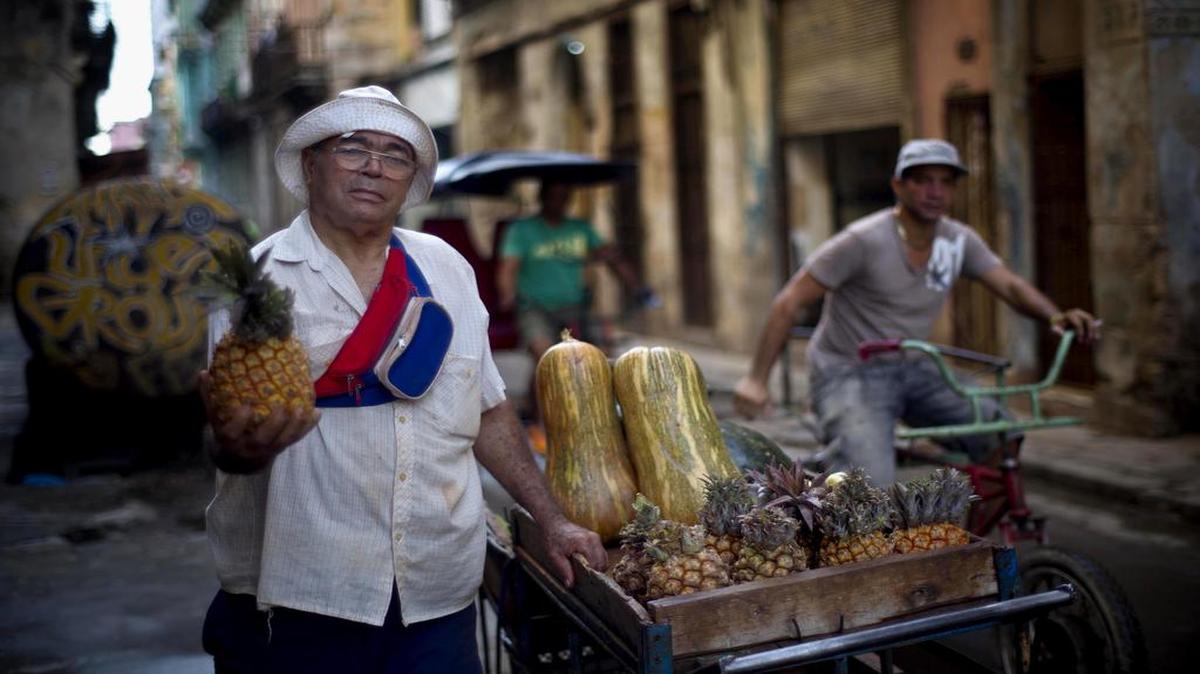 Edmundo Gómez, vendedor callejero de frutas, posa con su carro de frutas y vegetales en una calle de La Habana, en una imagen del 26 de diciembre del 2014.