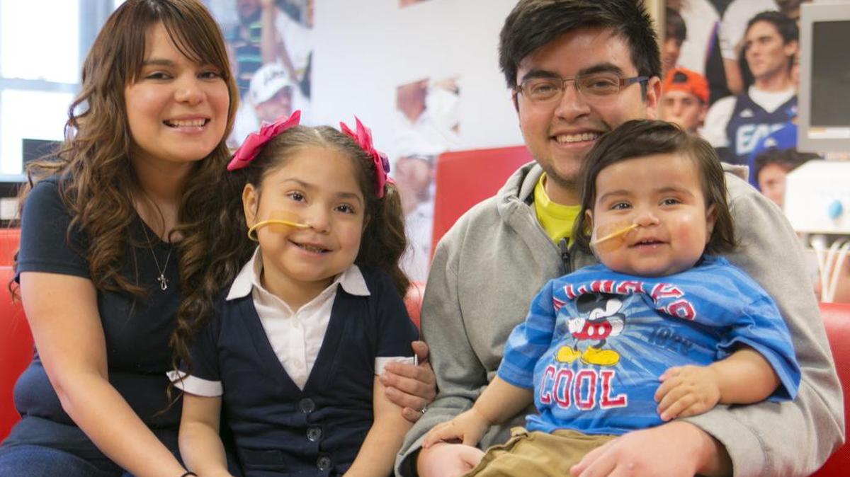 Julissa Cerda abraza a su hija Delilah Valdez, mientras su esposo, José Garza, carga en sus piernas a Liam Garza que recibió un trasplante de ocho órganos en el Jackson Memorial Hospital.