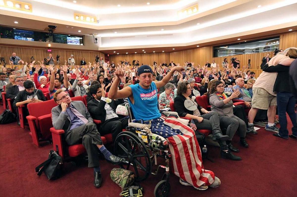 Chaunce O ‘Connor, gives a thumbs-down signal while the rest of the audience has their hands up in support, during a heated debate on President Donald Trump’s immigration policy at the Feb. 17, 2017 meeting of the Miami-Dade County Commission.