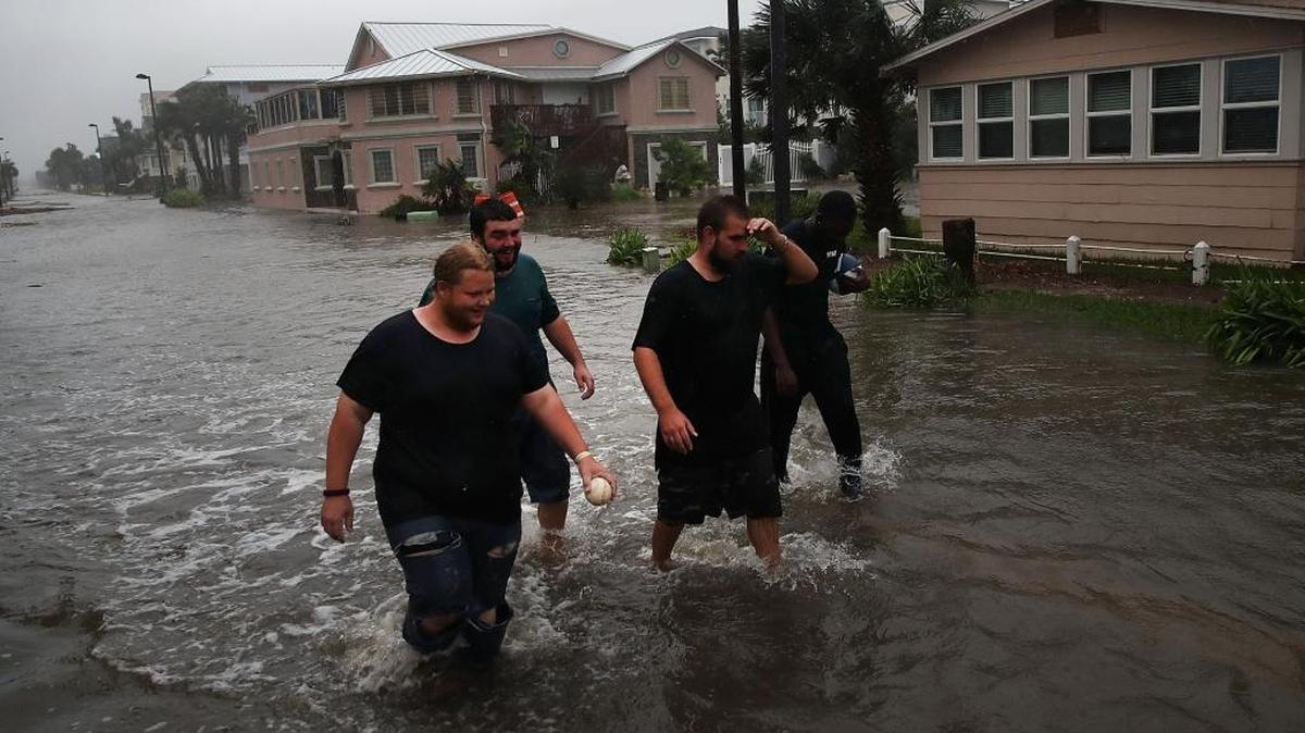 Joel Thompson (izq.), Brandon Smith, Bernie Lucas y Christian Heaton caminan por las calles inundadas de Jacksonville Beach luego del paso del huracán Matthew el viernes.
