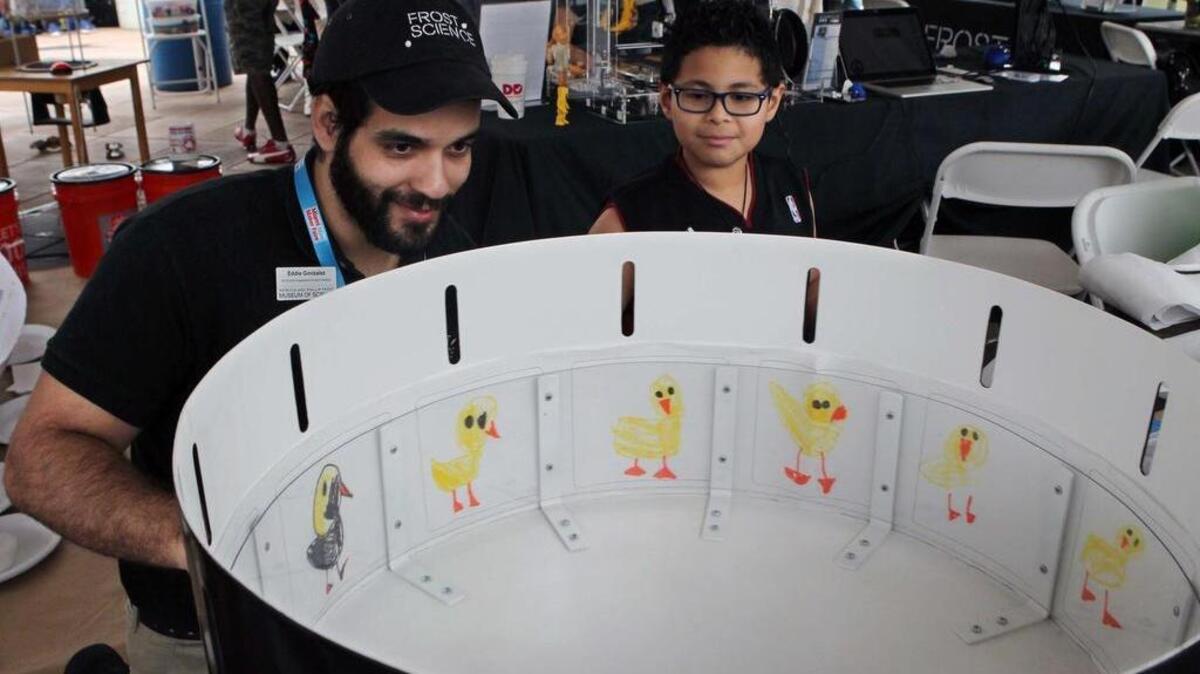 Eddie González, instructor del Frost Museum of Science, muestra al pequeño Joseph López un zoótropo en el Miami Mini Maker Faire.