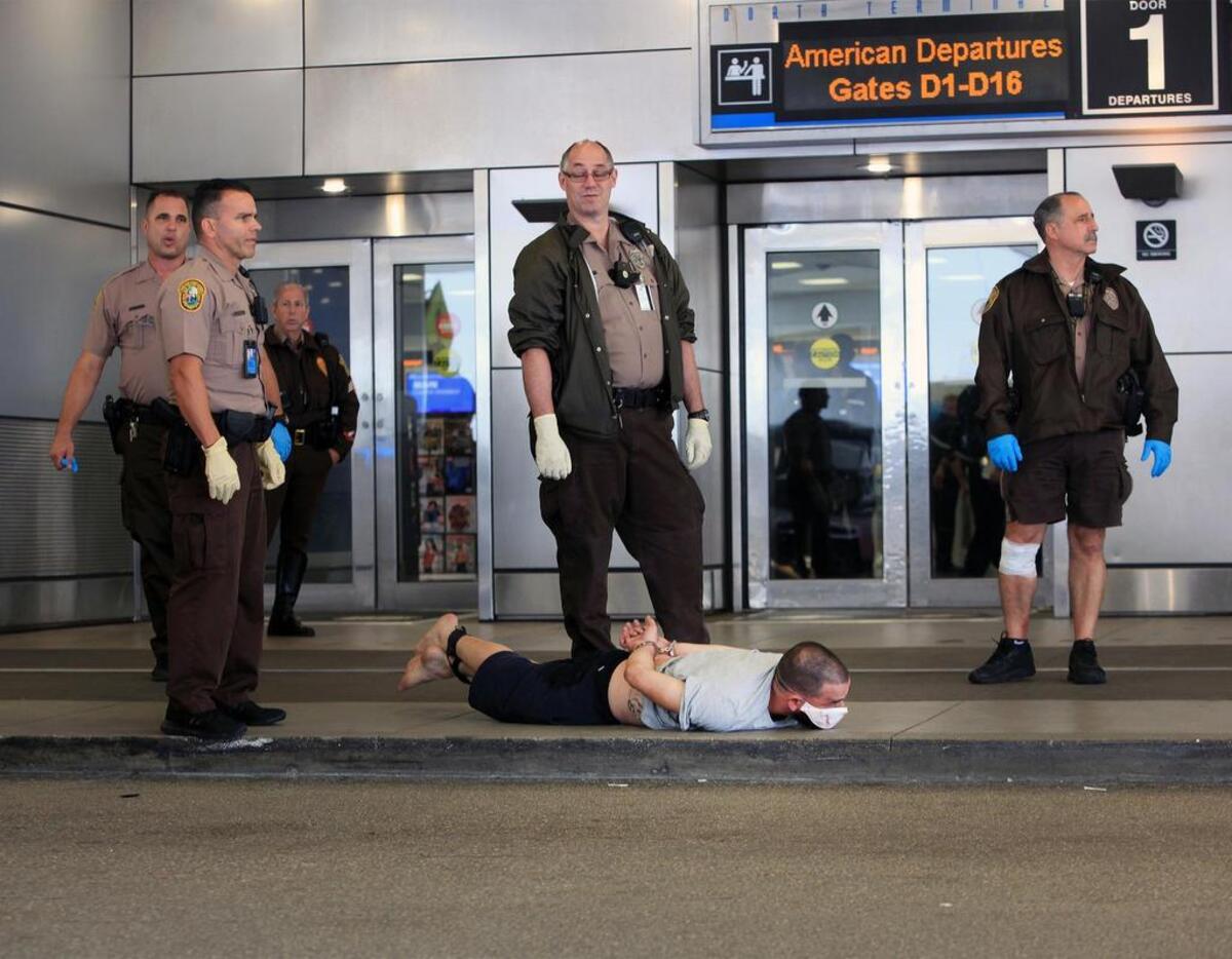 La policía de Miami-Dade vigila a un hombre que yace en el suelo frente al Concourse D en el Aeropuerto Internacional de Miami después de un aparente altercado el miércoles 25 de octubre de 2017.