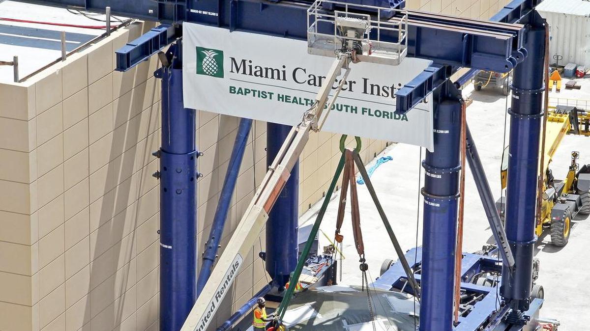 Una máquina de 220 toneladas capaz de acelerar partículas de protones altamente cargadas para su uso en la terapia de radiación de la oncología, es colocada por trabajadores en el Baptist Hospital de Miami.