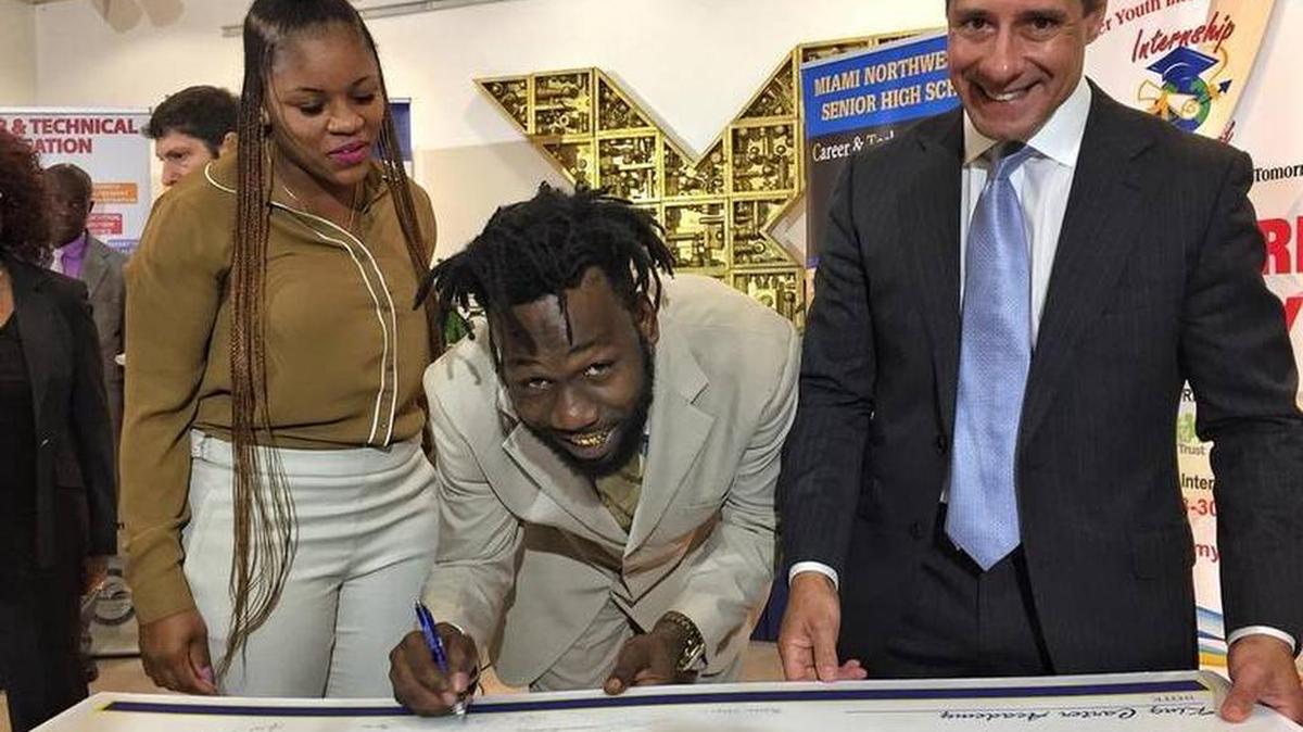 Monica Smith y Santonio Carter, los padres de King Carter, junto a Alberto Carvalho, superintendente escolar de Miami-Dade, frente al cheque de $1 millón entregado al distrito escolar.
