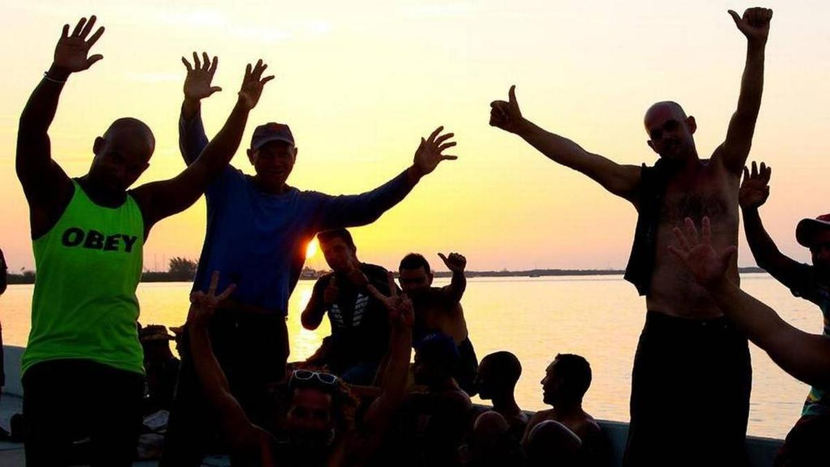 A su llegada a Estados Unidos, un grupo de inmigrantes cubanos saluda antes de ser procesados por la Guardia Costera en Cayo Hueso, en agosto del 2015.