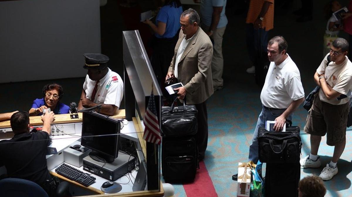 Un funcionario de control de pasaportes adscrito a la oficina de Adunas y Protección de Fronteras (CBP) verifica los pasaportes de viajeros que arriban al Aeropuerto Internacional de Miami. Archivo
