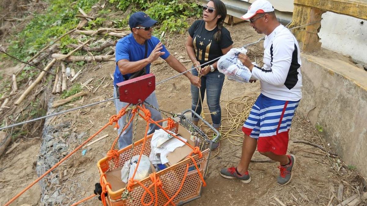 Los hermanos Saul Aldarondo, izquierda, y Luis Aldarondo, junto a Mary López llenan un carrito con artículos necesarios en la comunidad de Río Abajo.