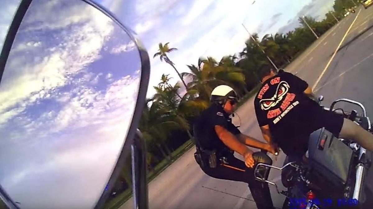 Un policía ayuda al comisionado del condado de Miami-Dade, José “Pepe” Díaz, a estabilizar la moto luego de detenerlo por manejar a alta velocidad.