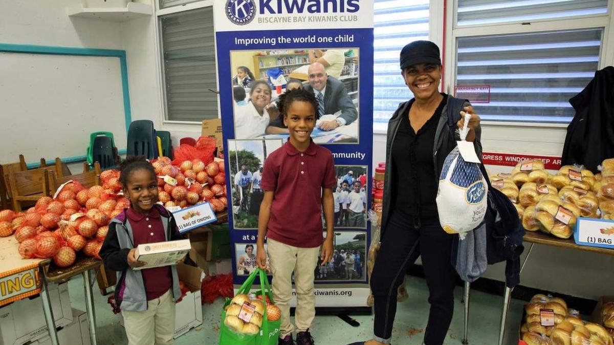 Los hermanos Jojo y Jeante Rivero con su madre María Rivero muestran el lunes los alimentos distribuidos por Kiwanis Club en la escuela Phillis Wheatley Elementary School.