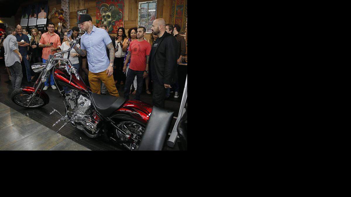 
El artista tatuador, Ami James (centro), y Andrés Torres (der.), presidente de Global Humanitaria, estudian la motocicleta a subastar, el sábado en South Beach.


