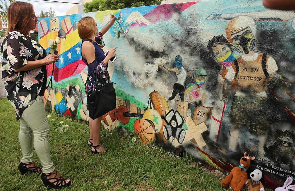 Maria Eugenia Tavares (izq.) y su hija Alejandra Carmona colocan flores en el mural homenaje a los caídos en las protestas antigubernamentales en Venezuela.